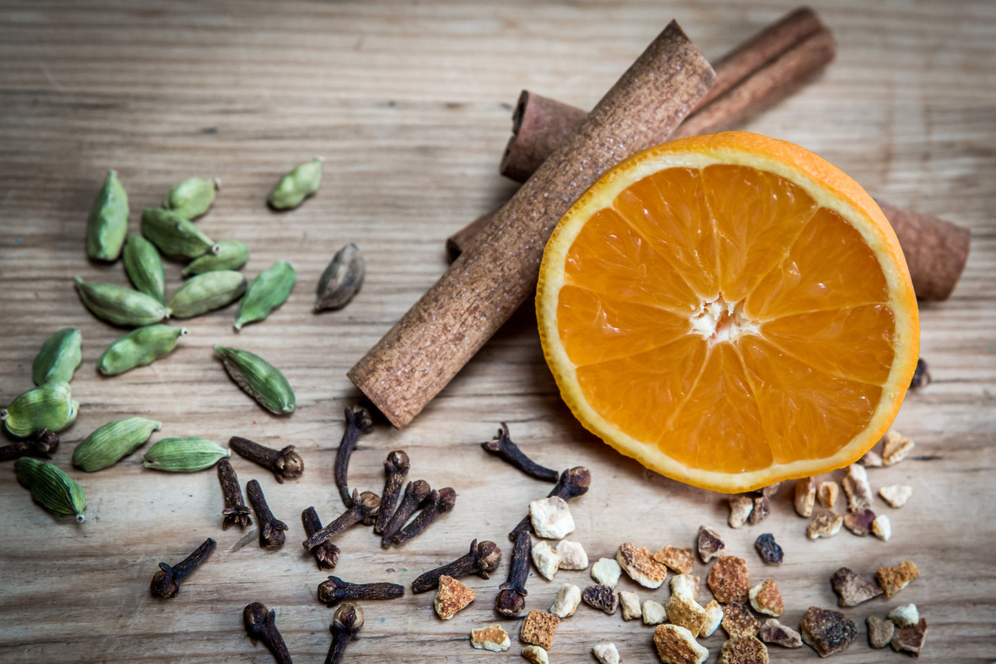 Orange half, cinnamon, cloves, cardamom and dried orange peel on wooden background