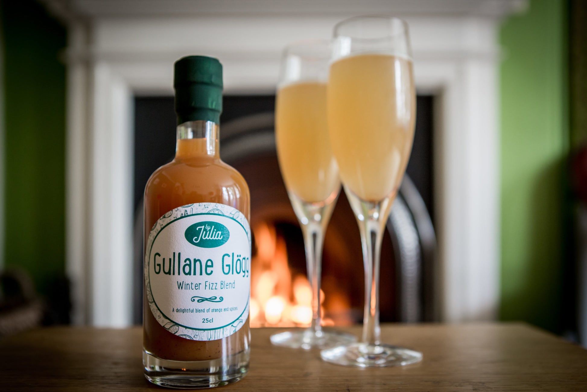Gullane Glögg Winter Fizz Blend and two wine glasses in front of fire